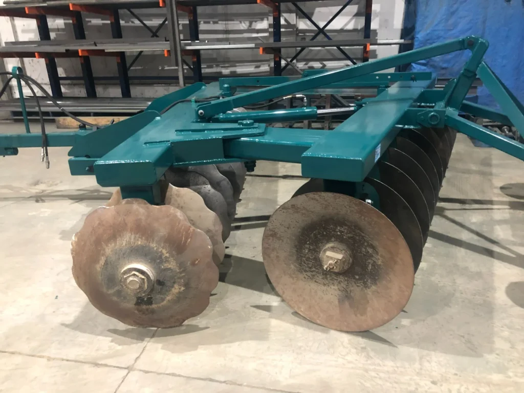 Detalle lateral de los discos del arado agrícola, con estructura metálica verde y discos en posición angular