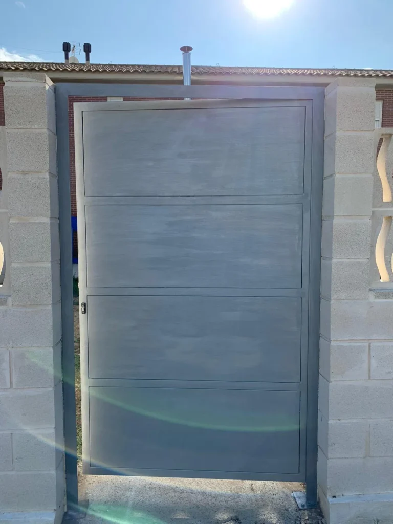 Puerta metálica gris colocada entre muros de bloques de hormigón
