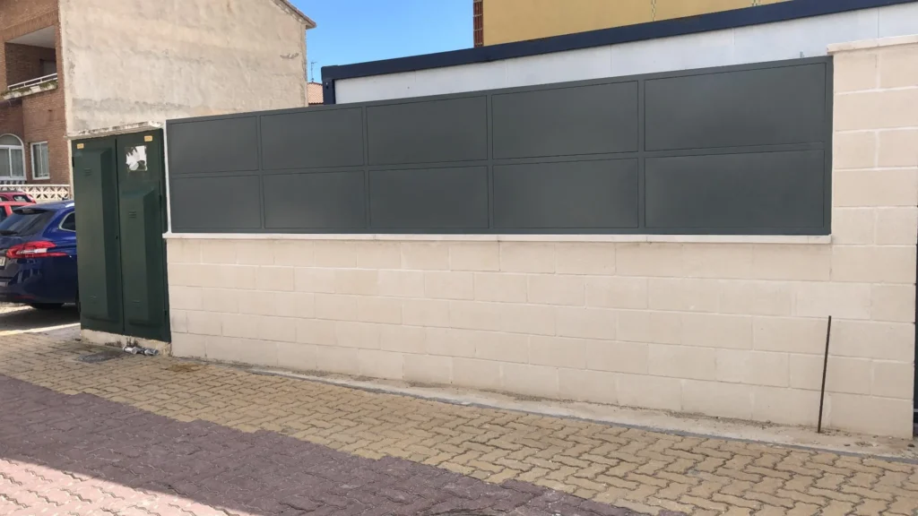 Paneles metálicos decorativos sobre muro de bloques en fachada urbana