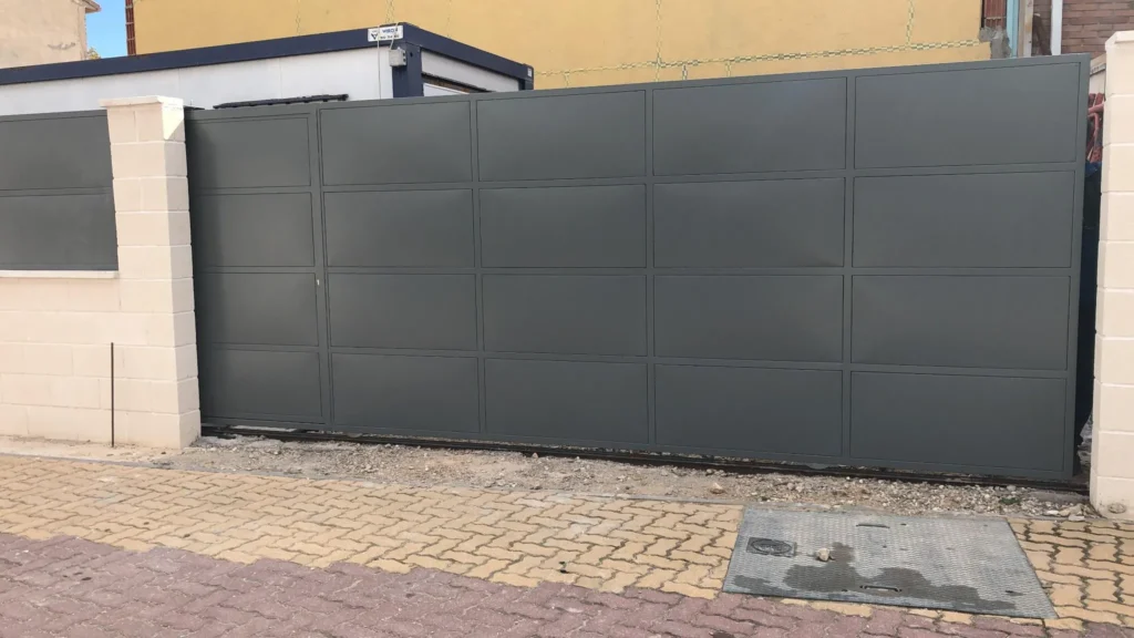 Puerta corredera abierta parcialmente, montada sobre guía inferior.