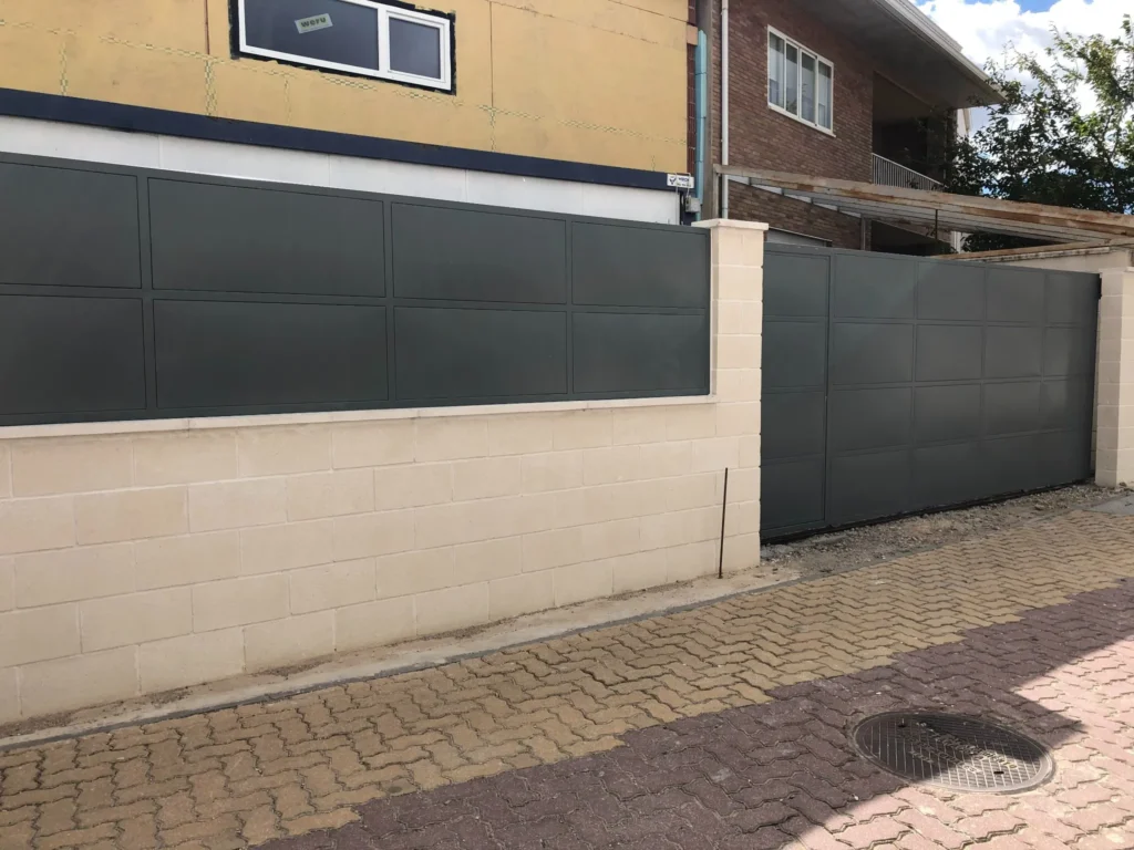 Vista lateral de conjunto de muro con paneles metálicos y puerta corredera.

