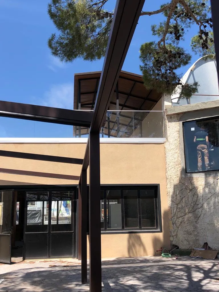 Estructura metálica exterior en construcción junto a edificio de dos plantas