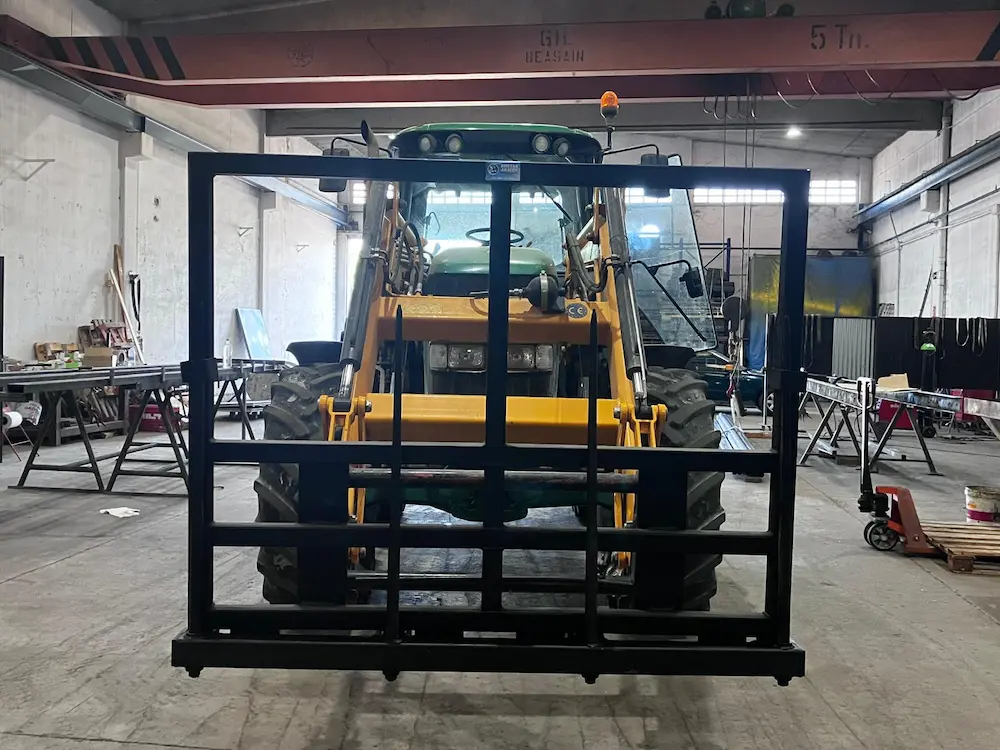 Tractor amarillo con una estructura negra delante en un taller